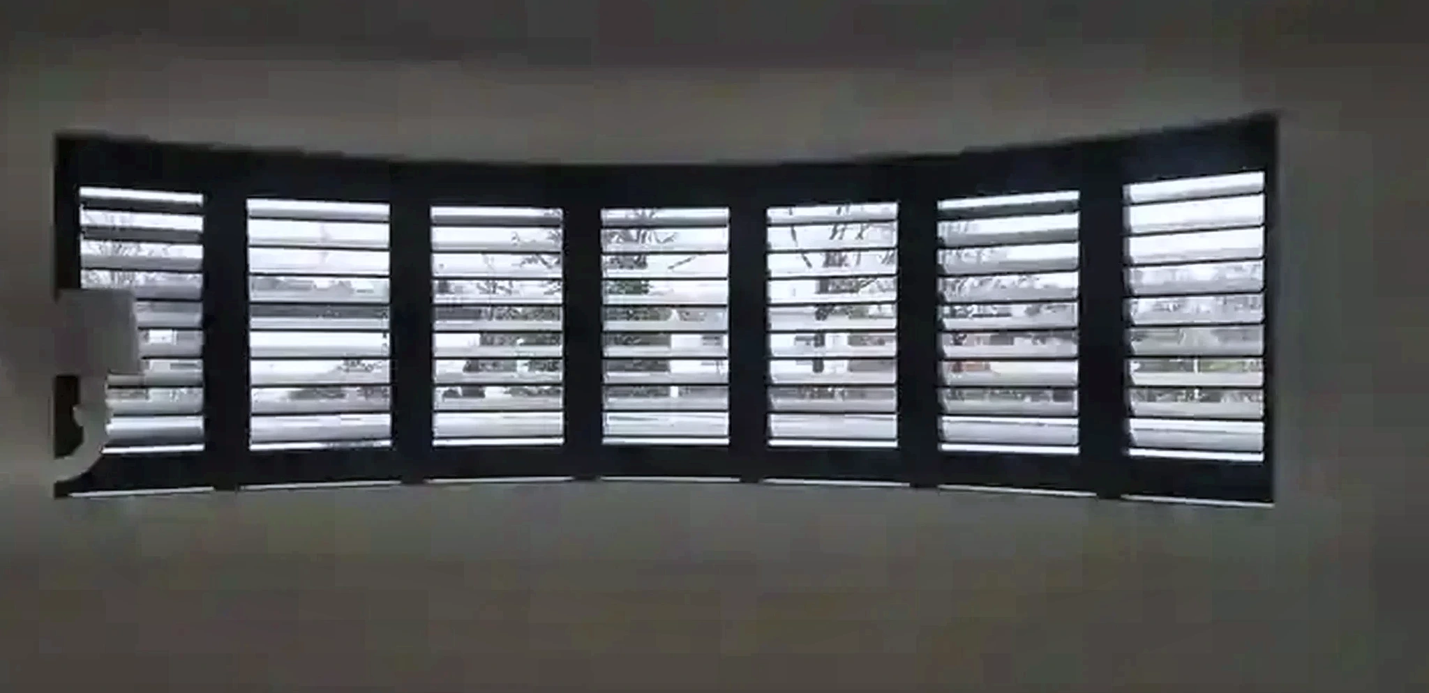 Donkere shutters in een gebogen raamopstelling