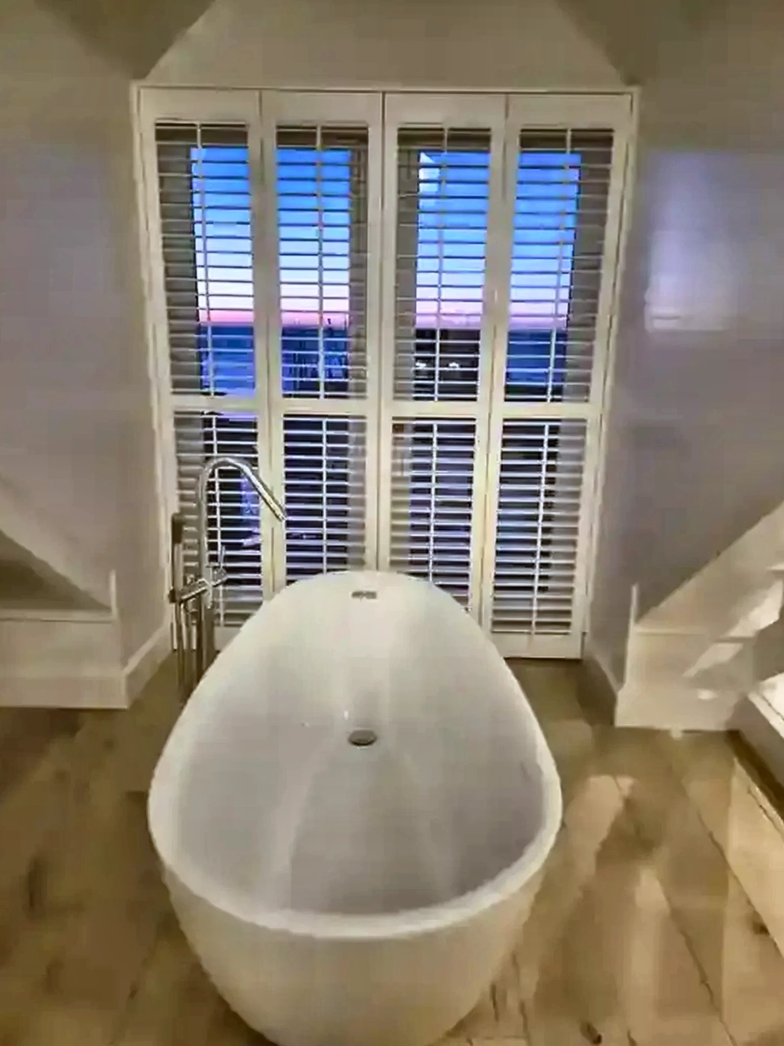Witte shutters achter een vrijstaand bad