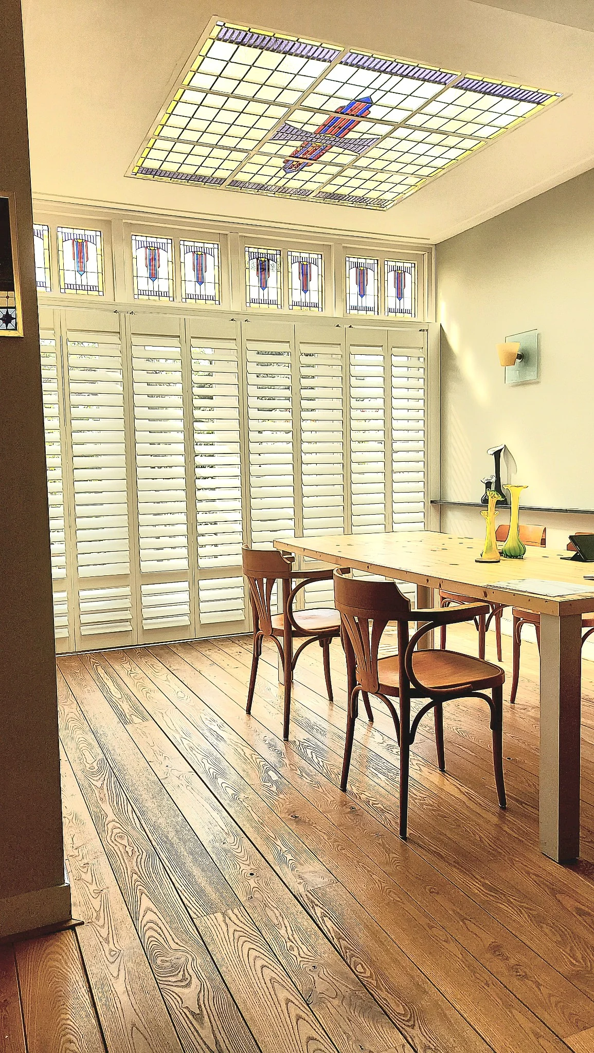 Witte shutters op rails onder glas-in-lood in Nijmegen