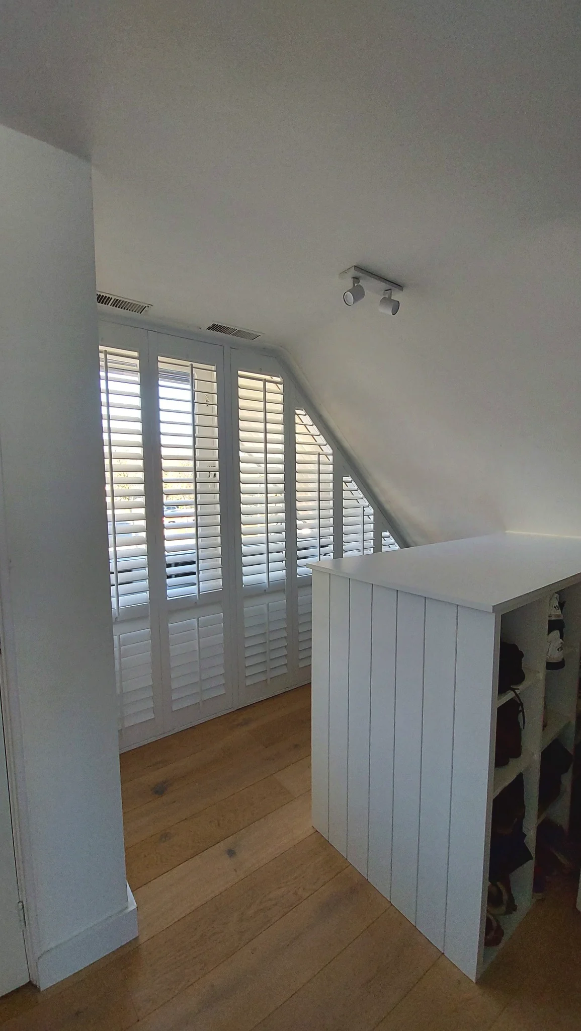 Witte shutters in een schuin slaapkamerraam in Weesp
